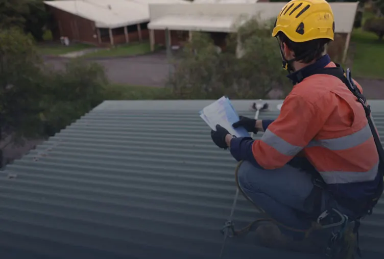 Crossy's roofer inspecting a metal roof during a restoration